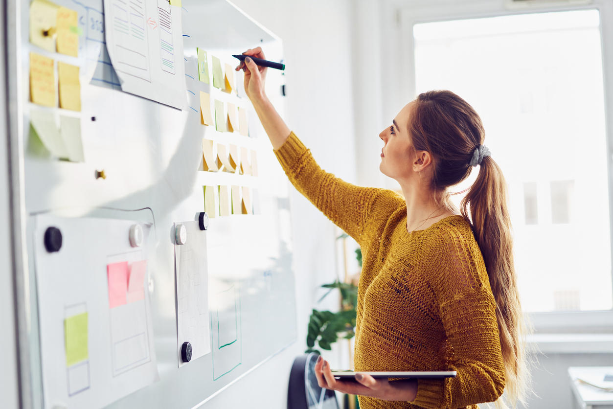 woman writing notes on a white board