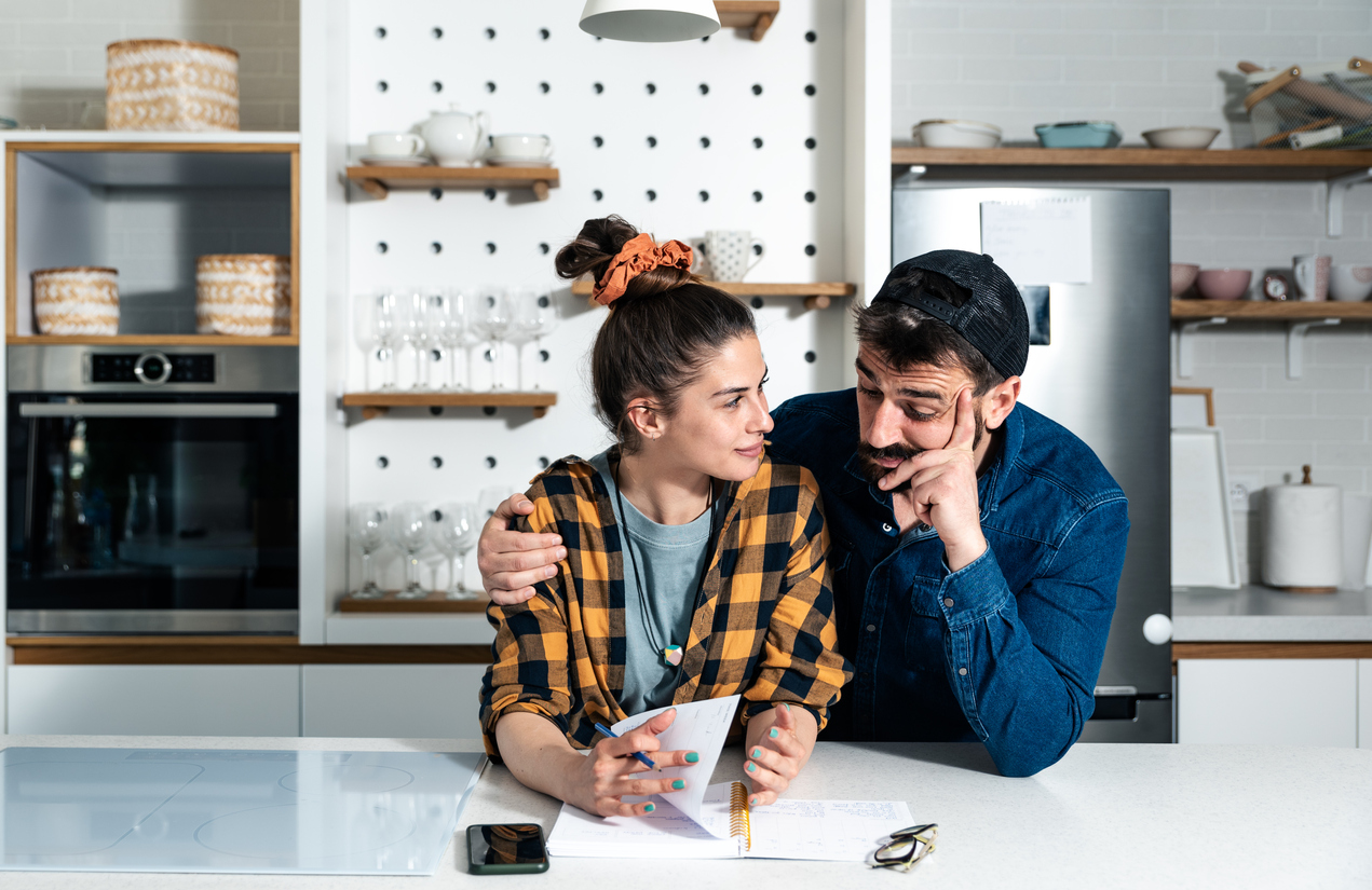 Young couple standing in the kitchen making a list 